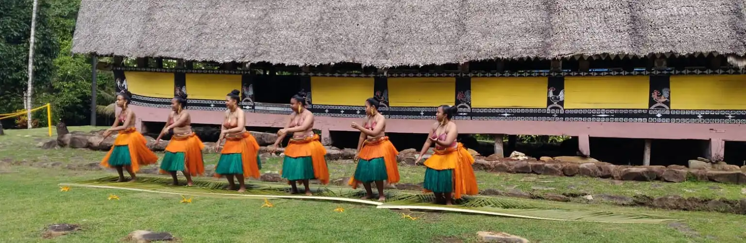 Local Palauan traditional dancers in front of a Bai, a men's house 