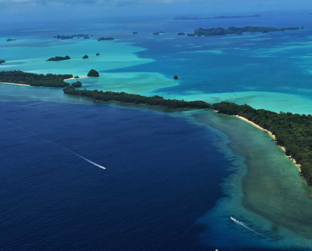 Aerial photo of Ngemelis Island and surrounding sea with a speed boat approaching the island